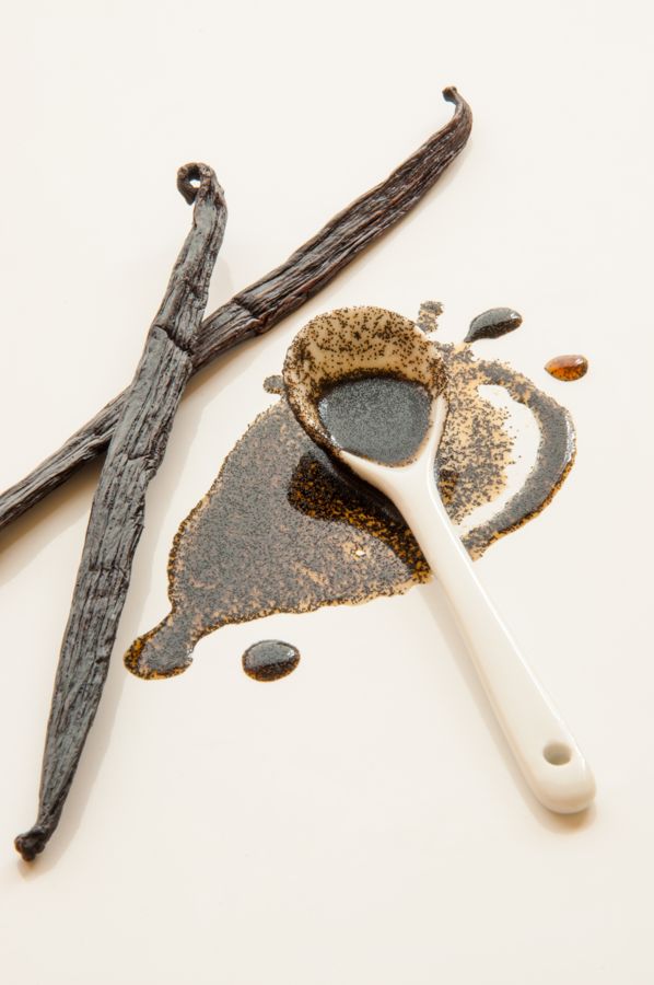 Vanilla beans beside a spoon of vanilla seeds